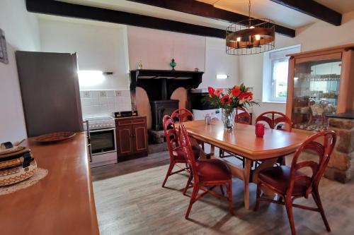 een keuken en eetkamer met een houten tafel en stoelen bij Ti va zud kozh in La Feuillée