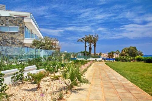a walkway in front of a house with palm trees at Sea Pearl Luxury Beachfront Villas in Ayia Napa