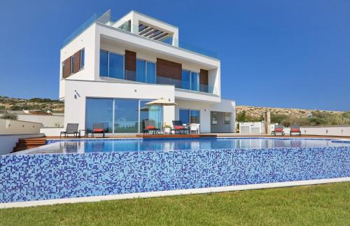 a villa with a swimming pool in front of a house at Sea Pearl Luxury Beachfront Villas in Ayia Napa