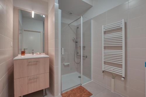 uma casa de banho com um chuveiro, um lavatório e um espelho. em OVELIA Rennes Chantepie - Le Patio Margot em Chantepie