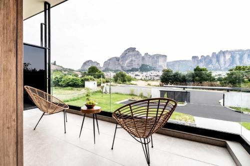 two chairs and a table on a balcony with mountains at Mirabilis Boutique Hotel by Panel Hospitality in Kalabaka