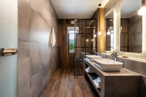 La salle de bains est pourvue de 2 lavabos et de 2 miroirs. dans l'établissement Mirabilis Boutique Hotel by Panel Hospitality, à Kalambaka