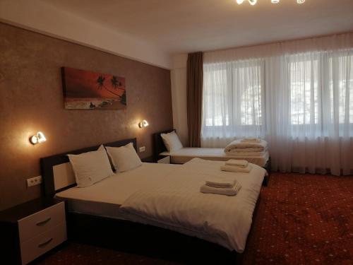 a hotel room with two beds and a window at Pensiunea Perla Codrului 