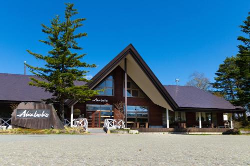 un gran edificio con un árbol delante en Nature Cottage Akabeko, en Kitashiobara