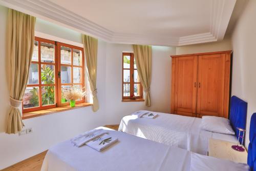 two beds in a room with two windows at Çınarlar Apart KC Blok in Kaş