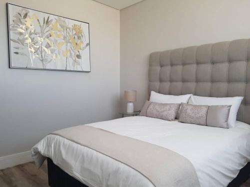 a bedroom with a large white bed with a picture on the wall at Movic's Modern Airbnb in Windhoek