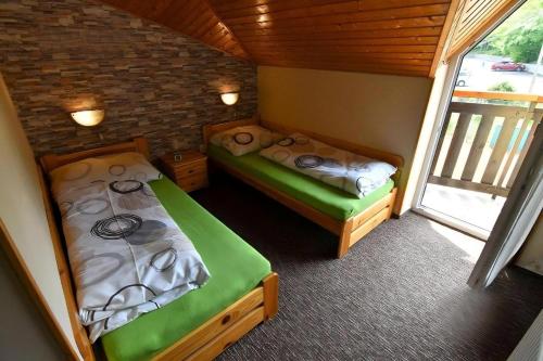 two beds in a small room with a window at Penzión Prameň in Vinné