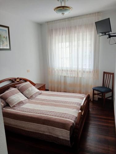 1 dormitorio con cama, ventana y silla en PENSION RESTAURANTE CASANOVA, en Puebla de Trives