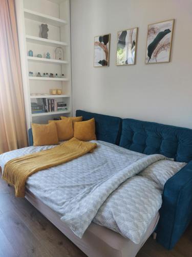 a bed in a room with a blue couch at Apartamencik przy Tężni w Konstancinie in Konstancin-Jeziorna