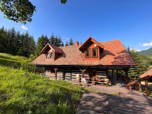 a log home with a deck and chairs in front at Chata Wetłyna II in Wetlina