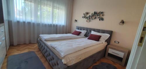 a bedroom with a bed with white sheets and red pillows at Dream Apartment Timisoara in Timişoara