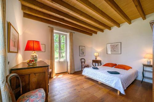 a bedroom with a bed and a table and a window at La Maison de Beaugas - Avec piscine dans le pays des bastides in Beaugas