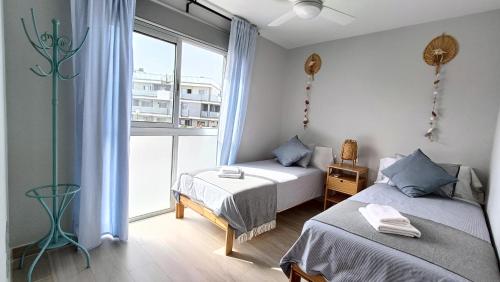 a bedroom with two beds and a large window at Amplio y cómodo apartamento. in Granadilla de Abona