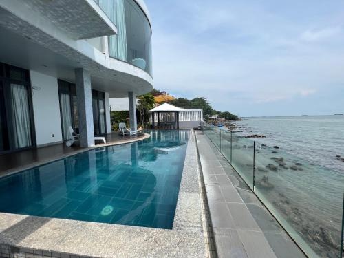 a building with a swimming pool next to the water at Nancy Tran Grand Strip Vung Tau Villa 10 in Vung Tau