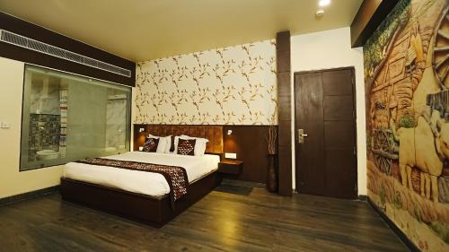 1 dormitorio con 1 cama y una pared con una pintura en Hotel Atulyaa Taj, en Agra