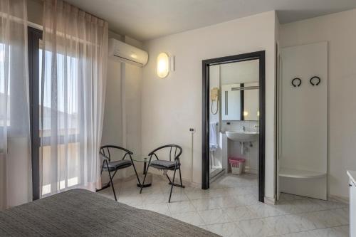 a bedroom with a bed and two chairs and a bathroom at Hotel Quisisana in Vada