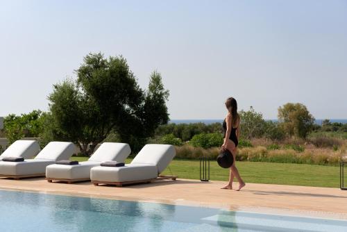 a woman walking next to a swimming pool at Aesthea 5-star Villa, 2Pools, Gym, Cinema, Sauna, By ThinkVilla in Prínos