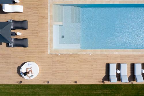 an overhead view of a pool with a person sitting on a chaise lounge at Aesthea 5-star Villa, 2Pools, Gym, Cinema, Sauna, By ThinkVilla in Prínos