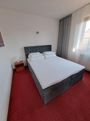a bedroom with a large white bed with a red carpet at Rezydencja Kwiatano - Basen & Jacuzzi & Sauna & Plac Zabaw in Grzybowo