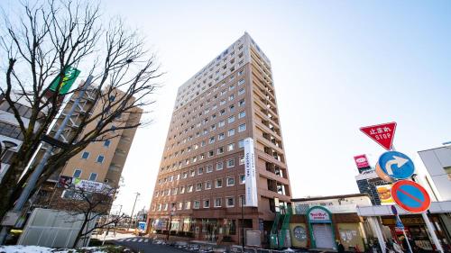 a tall building on a street in a city at Toyoko Inn Tokyo Fussa Ekimae Higashi guchi in Fussa