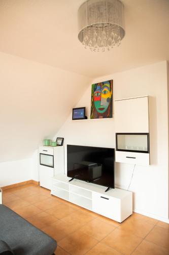 a living room with a tv and a white entertainment center at Art & Nature Apartments in der Nähe FFM-Messe in Bad Vilbel