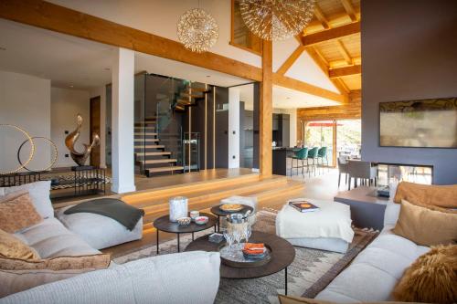 a living room with couches and tables and a staircase at Chalet Bella Cha - OVO Network in La Clusaz