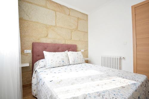 una camera con un letto e un muro in pietra di Casa con jardín en Pontevedra a Pontevedra