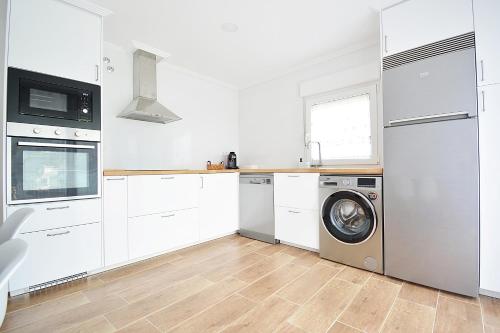 eine Küche mit weißen Schränken, einer Waschmaschine und einem Trockner in der Unterkunft Casa con jardín en Pontevedra in Pontevedra