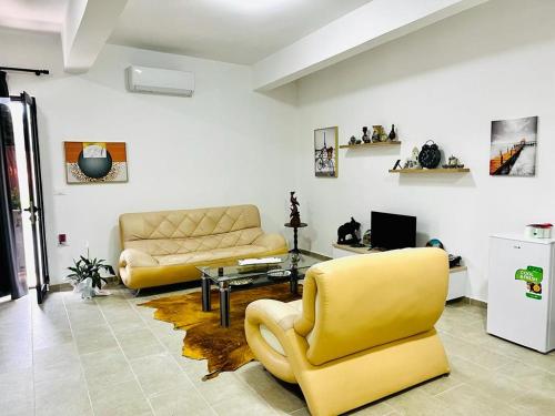 sala de estar con 2 sillas amarillas y sofá en Mili apartments, en Berat