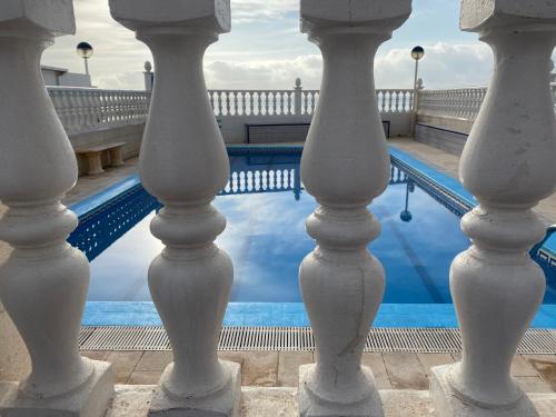 Una vista de una piscina a través de las columnas de un edificio. en The Manga Beach Sea view Studio, Sandy beach & Crystal clear water, 5G Wifi & Airco, en La Manga del Mar Menor