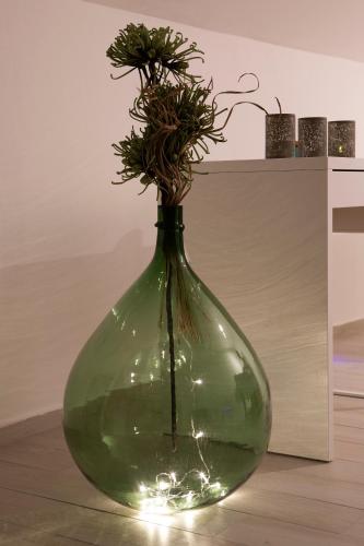 a green glass vase with a plant in it at Boutique Hotel Intermezzo - Pag centre in Pag