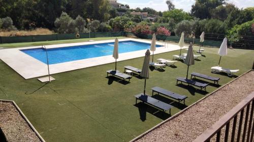 a swimming pool with lounge chairs and umbrellas at Apartamentos Turísticos La Castilleja in Córdoba