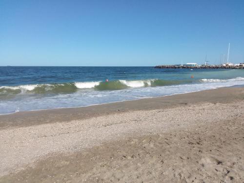 a sandy beach with waves in the ocean at Gradina 5 elemente in Eforie Nord