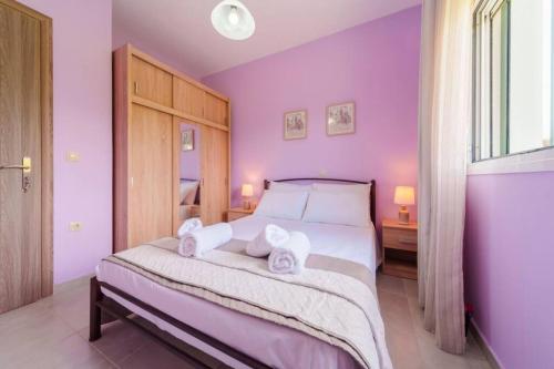 a bedroom with purple walls and a bed with two towels at Irene's Olive Guest house in Sami