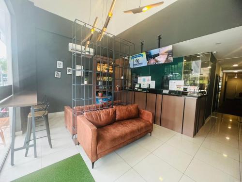 a living room with a brown couch and a bar at Smile Hotel Subang Airport in Shah Alam