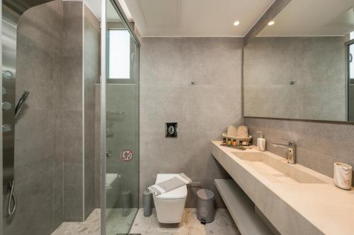 uma casa de banho com um chuveiro, um lavatório e um WC. em Ethereal Villas Chania em Daratso