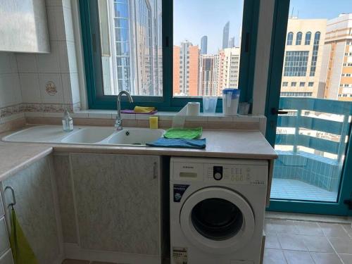 uma cozinha com um lavatório e uma máquina de lavar roupa em Abu Dhabi Downtown 3 bedroom Penthouse Apartment em Abu Dhabi
