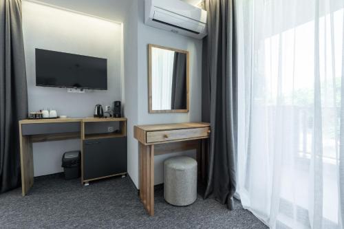 um quarto com uma secretária, um espelho e uma televisão em Къща за гости "Лилия 5" em Lozenets