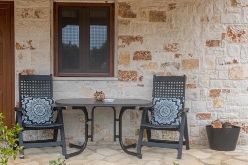 una mesa y dos sillas sentadas junto a una pared de piedra en okakosolykos en Kostitsi