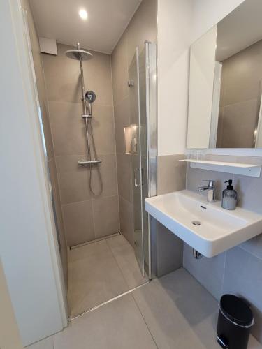 ein weißes Bad mit einer Dusche und einem Waschbecken in der Unterkunft Pura Vida House – Bükfürdő in Bük