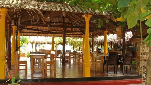 a restaurant with wooden tables and chairs under a pavilion at Rupa's Hotel in Arugam Bay