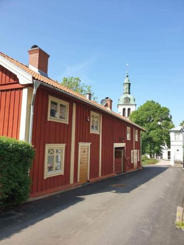 czerwony budynek z wieżą zegarową w tle w obiekcie Kyrkstallet 1 Historiskt med bästa läge Gränna w mieście Gränna