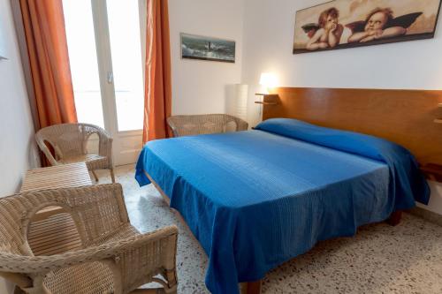 a bedroom with a blue bed and wicker chairs at Appartamento Selinunte in Marinella di Selinunte