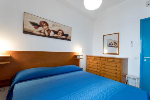 a bedroom with a blue bed and a painting on the wall at Appartamento Selinunte in Marinella di Selinunte