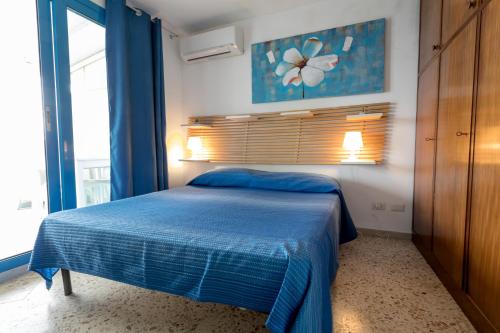 a bedroom with a blue bed and a window at Appartamento Selinunte in Marinella di Selinunte