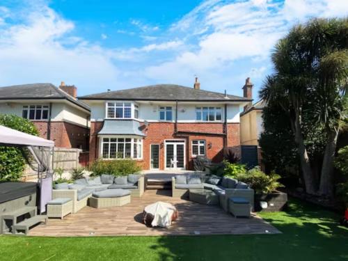 a woman laying on the lawn in front of a house at Four Bedroom Family Abode with Hot Tub, Garden and BBQ in Bournemouth