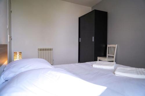 a bedroom with a white bed and a black cabinet at L'Eden Urbain・Stationnement Facile・Proche Centre in Châteauroux