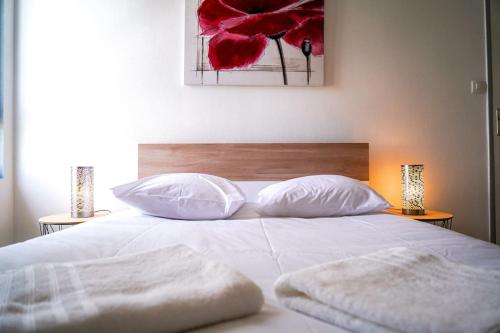 a white bed with two pillows on top of it at L'Eden Urbain・Stationnement Facile・Proche Centre in Châteauroux