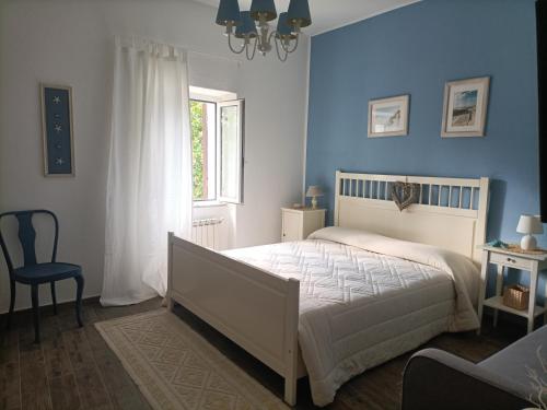 - une chambre avec des murs bleus, un lit et une chaise dans l'établissement Casa Indipendente Le Manie Finale Ligure, à Finale Ligure