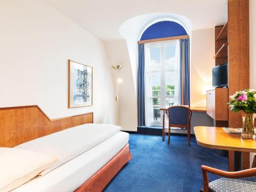 ウィーンにあるLiving Hotel Kaiser Franz Josephのベッドとテーブルが備わるホテルルームです。